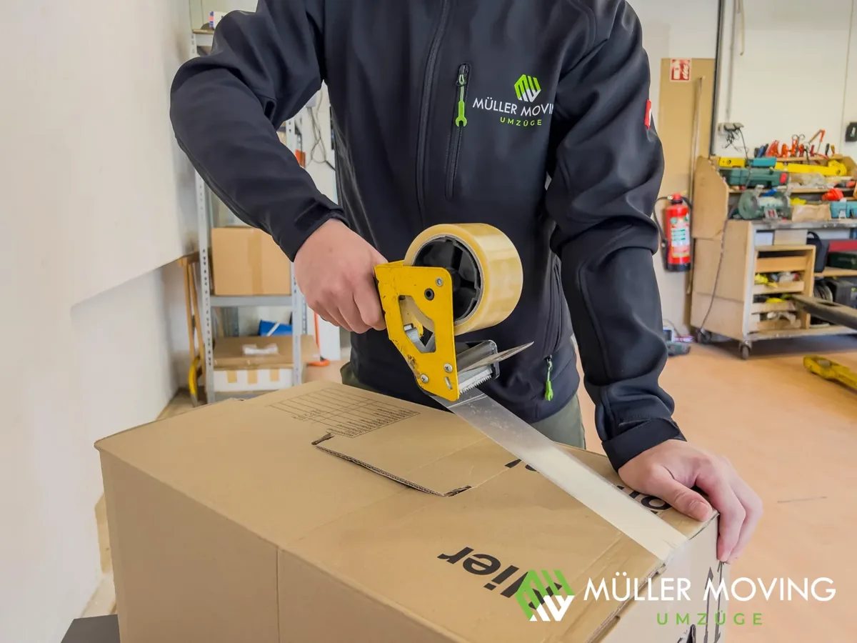 Müller Moving Mitarbeiter verschließt sorgfältig einen Umzugskarton